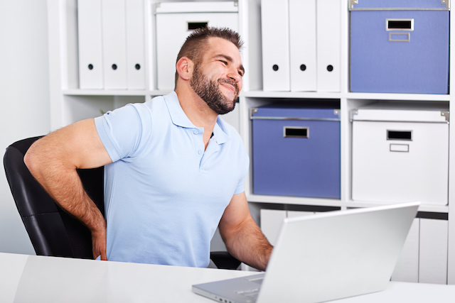 This is a picture of a man at a desk with low back pain.  You can help prevent low back pain with regular chiropractic care.